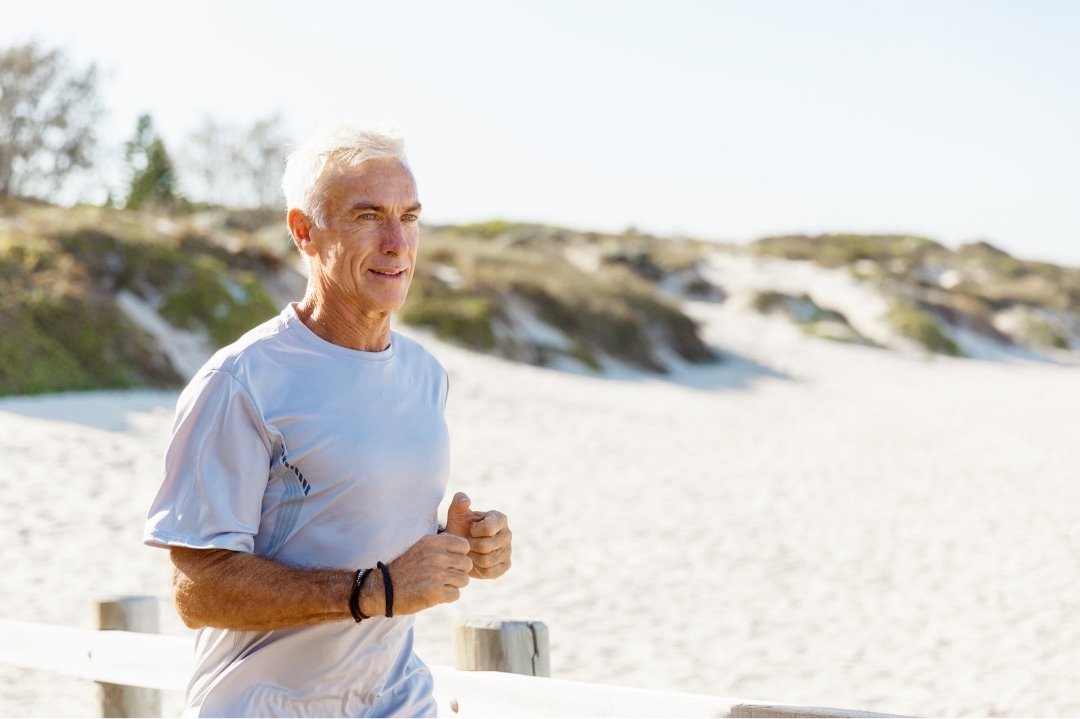 Older man running along a beach boardwalk — back to full activity after hernia repair